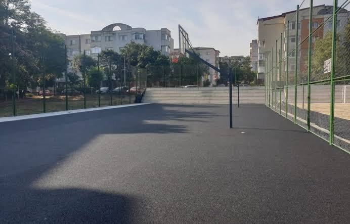 Aszfaltozott sportpálya kosárlabdapalánkkal, kerítéssel