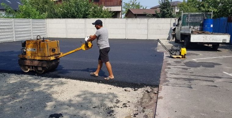 Udvar aszfaltozás tömörítése kézi hengerrel kerítés mellett